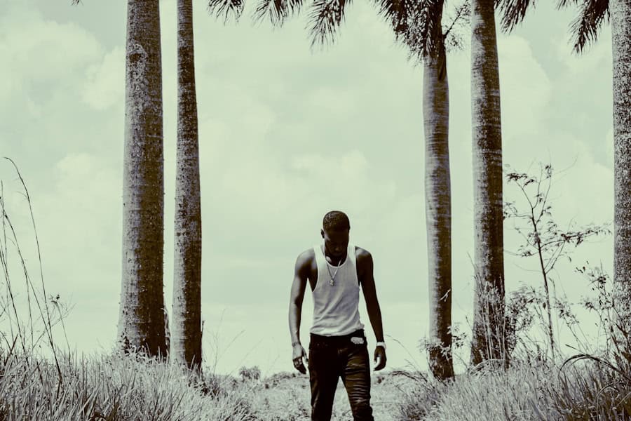 Young man walking through a scenic outdoor trail with tall palm trees in the background, highlighting eco-friendly outdoor activities and sustainable living.