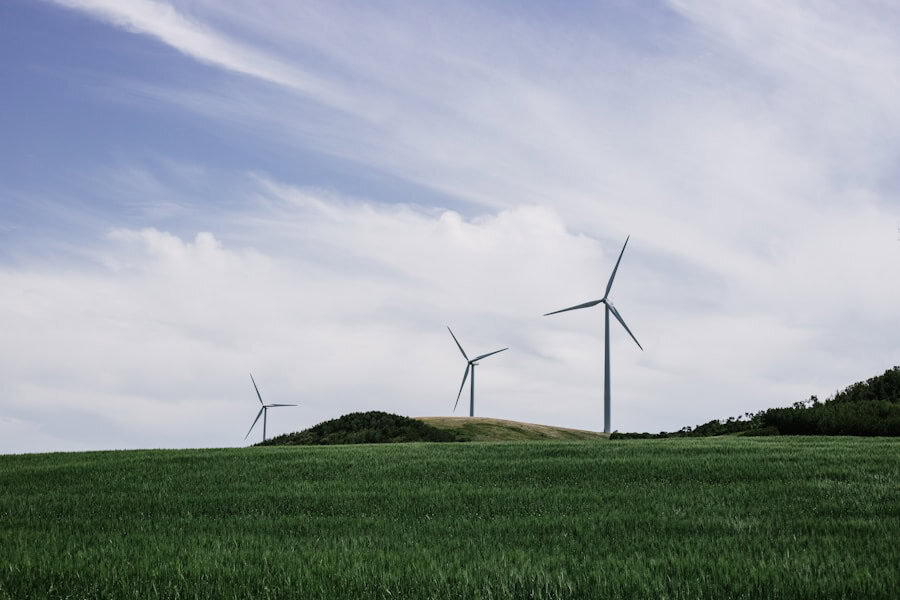 Wind turbines on a green hill under a partly cloudy sky, representing renewable energy and eco-friendly sustainable practices for eco-conscious homes.